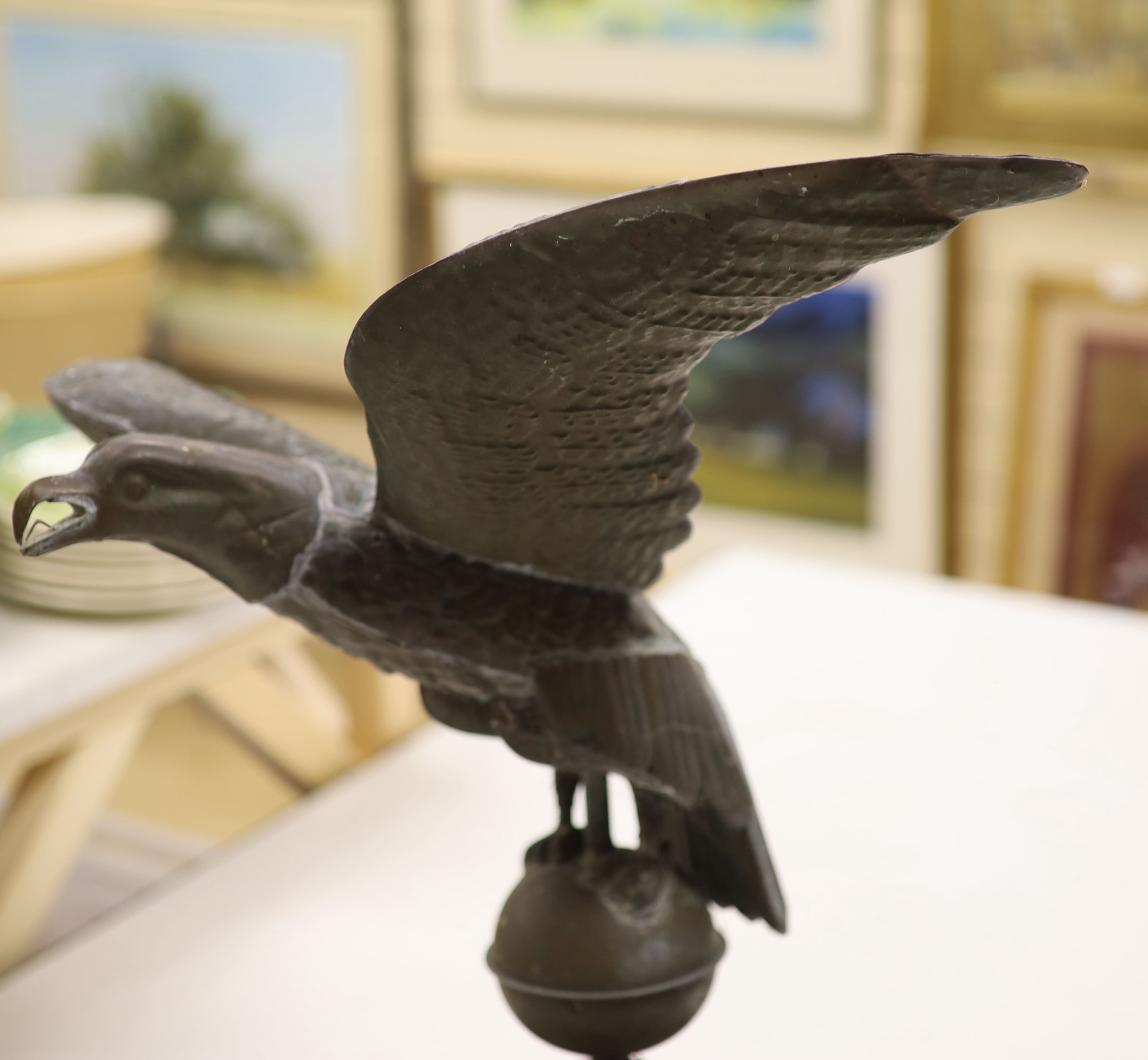 A 19th century American copper weather vane, modelled as an eagle, on an associated wooden base, width 62cm height 58cm